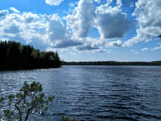 Lake view with bright blue sky, white clouds, forest background