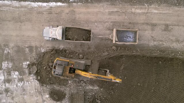 Aerial birds eye view of a excavator loading dirt into a dump truck in a construction site