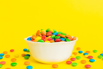Multicolored candies in a bowl on a colored background. birthday and holiday concept. Top view with copy space