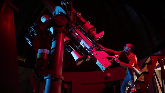 Astronomer with a big astronomical telescope in observatory doing science research of space and celestial objects.