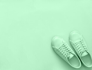Green sneakers on green background, copy space