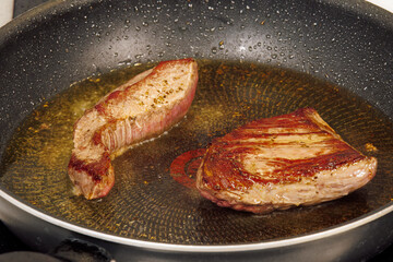 Top sirloin marbled American beef steak on a pan. High-angle focus on cooking meat with olive oil.
