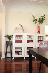 A lived in dinning room with table china cabinet and plant stand