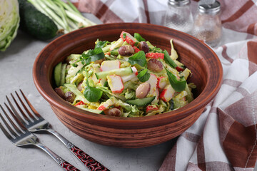 Salad with cabbage, crab sticks, beans, eggs and cucumber in brown bowl