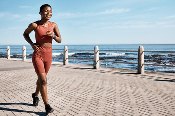 Black woman running at beach promenade for fitness, energy and strong summer body. Runner, healthy female and sports wellness at ocean for marathon goals, cardio exercise and workout in sunshine - obrazy, fototapety, plakaty