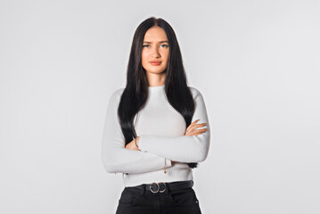 Portrait of serious lady posing with folded arms over white studio background. Confident young woman in closed posture. Office professions