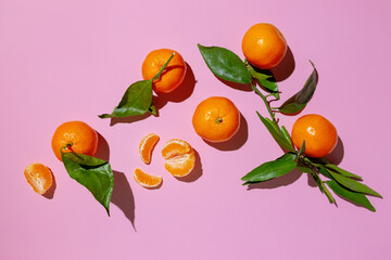 Fresh tangerine with leaves on pink background.
