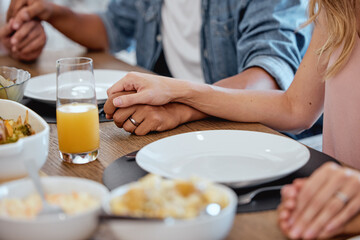 Holding hands, praying and food with a family grace around the dinner table during a thanksgiving celebration. Prayer, trust and love with a group of people enjoying lunch during a social gathering