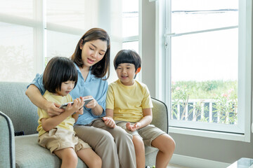 Happy Asian family male and female parents Teaching or helping with their children's homework. On holiday. Staying at home happily.