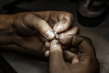 Smeared with soot in the hands of a goldsmith, holding jewelry (ring) close