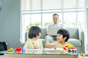 Obraz na płótnie Canvas Happy Asian family male and female parents Teaching or helping with their children's homework. On holiday. Staying at home happily.