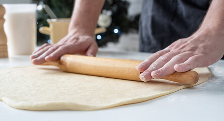 Male chef working with dough, cooking cinnamon rolls