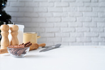 kitchen table with baking tools, cinnamon and christmas tree in the background