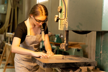 A female carpenter is working at a furniture factory with modern equipment and machinery.