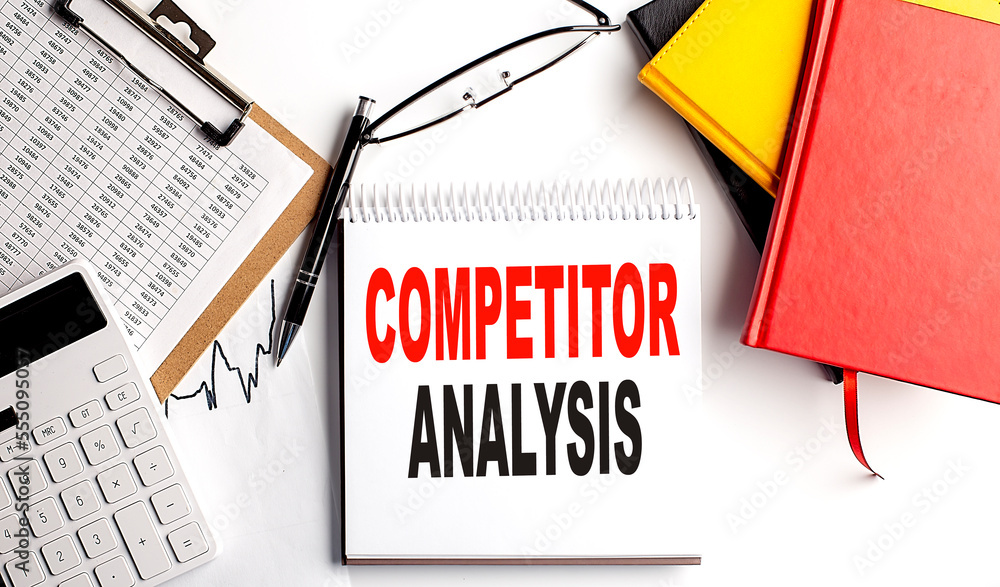 Aufkleber competitor analysis text on notebook with clipboard and calculator on white background