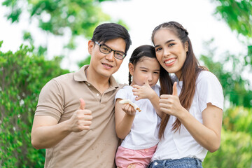 Young Asian parents doing activities eating and playing with their daughter in the front yard during the holidays happily.