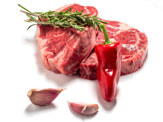 Fresh premium rib eye steak on white isolated background with green herb and garlic clove and red pepper. Premium beef cut. Top quality meat.