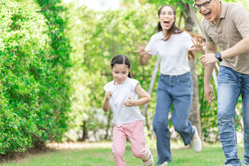 Fototapeta premium Young Asian parents doing activities eating and playing with their daughter in the front yard during the holidays happily.