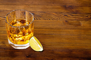 Glass of golden whiskey with ice. Strong alcoholic drink background