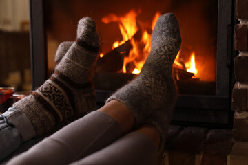 Couple resting near fireplace indoors, closeup. Winter vacation