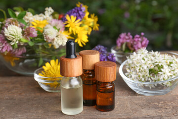 Fototapeta na wymiar Bottles of essential oils and many beautiful flowers on wooden table