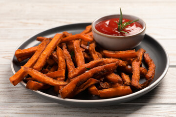 Delicious sweet potato fries served with sauce on white wooden table, closeup