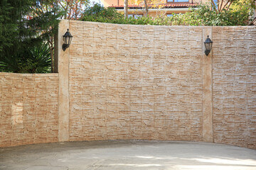 Beautiful old brick wall with lanterns near concrete sidewalk outdoors