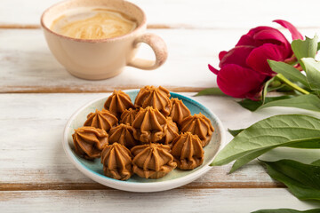 Homemade soft caramel fudge candies on white wooden, side view, close up.