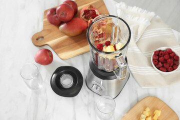 Blender with smoothie ingredients on white marble table in kitchen, above view