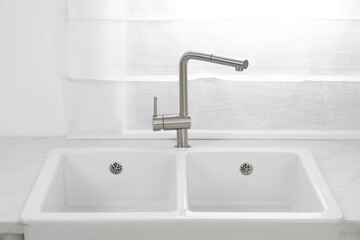 Modern sink and water tap near window in kitchen. Interior design