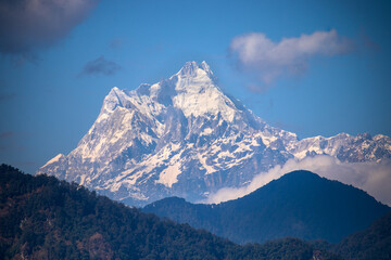 Kangchenjunga, also spelled Kanchenjunga, Kanchanjangha, and Khangchendzonga is the third-highest mountain in the world. The snow-clad peak of the mountain towers above the thick green forest.