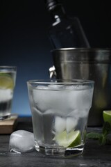 Glass of vodka with lime and ice on black marble table