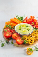 Vegetable tray with green peas and cream cheese dip on a light concrete background. Vegetarian recipes.