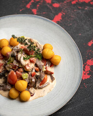 Beef with vegetables in sauce. Dish on plate on dark background. Close-up. Top view. Soft focus. Copy space. 