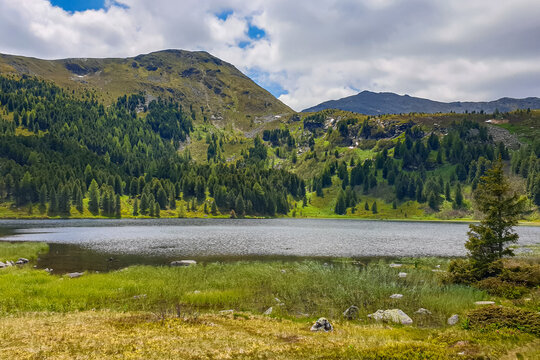 Panoramic view of alpine lake Winterleitensee surrounded by fir forest near Zirbitzkogel, Seetal Alps, Styria (Steiermark), Austria, Europe. Idyllic hiking trails in summer over alpine green pastures
