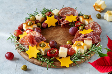 Christmas appetizers wreath on wooden board and grey background, star of Christmas plant or Poinsettia, napkin, forks