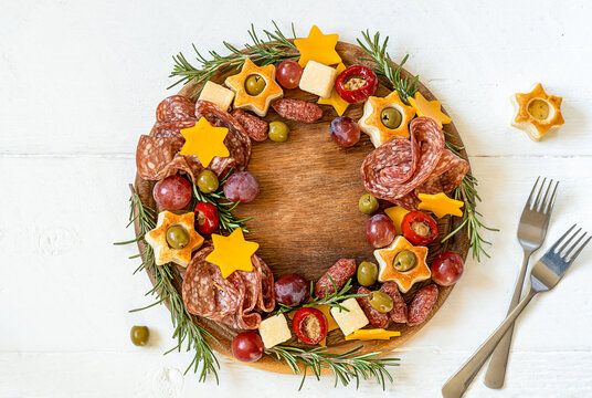 Christmas charcuterie board made in wreath shape on wooden cutting board and white wooden table 