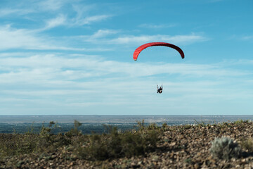 Red paragliding take offs on beautiful blue sky with clouds