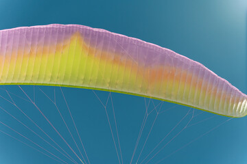 Close up of multi colored paraglider on beautiful blue sky