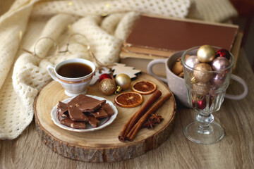 Cup of tea or coffee, various sweets and spices, Christmas decorations, comfy blanket, books and glasses. Selective focus.