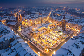 Snow covered old town in Krakow with a view of the Christmas Market photographed in the blue hour.