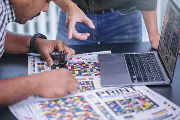 Crop image of worker checking print quality of media graphics proof print in printing industry....