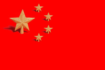 One large gold Christmas star ornament with four smaller ones standing on a red background. China Christmas, New Year and National day concept flag.