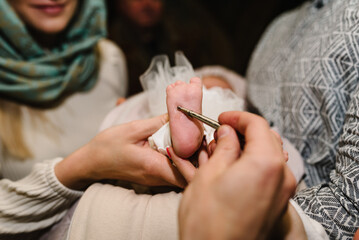 Baptism ceremony of a baby. Close up of tiny baby feet, the sacrament of baptism. The godfather...