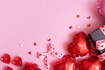 Red heart shape baloons, candels and present box on pink background. Valentines Day romantic background with copy space