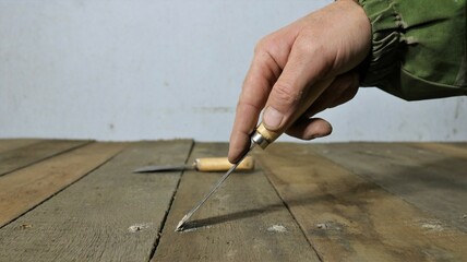 a hand with a narrow spatula covers with mastic small holes from a nail hammered into wood, smearing with a solution of cracks and holes on the surface of a wooden covering of a shelf or floor
