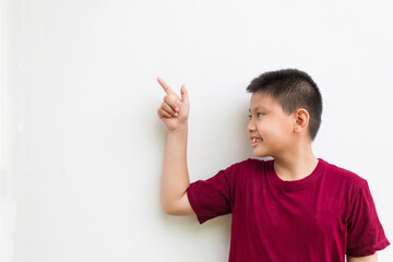 Smiling happy Asian boy pointing his finger away at copy space isolated over a plain white background