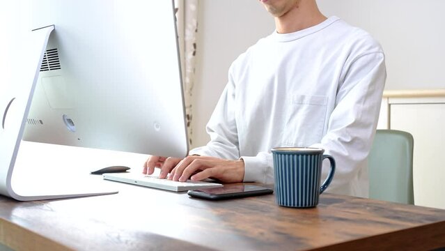 自宅でタイピング作業をする30代の男性
