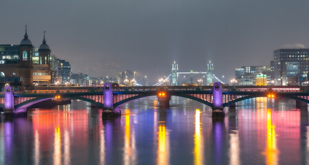 Obraz premium Panoramic view of the City of London and the London Bridge over the river Thames, illuminated at night