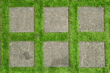 Flat lay shot of tile pavement close-up with artificial green grass. Abstract background texture.